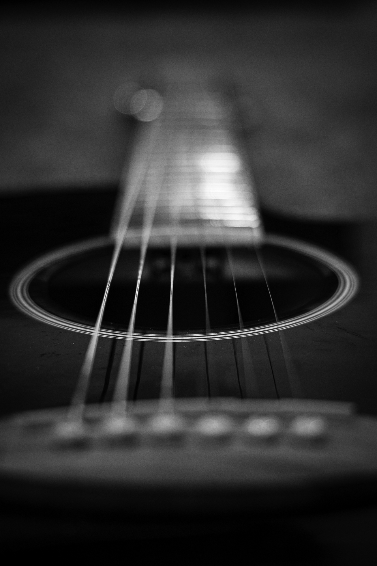 Blurry close-up of the neck and sound hole of a guitar.