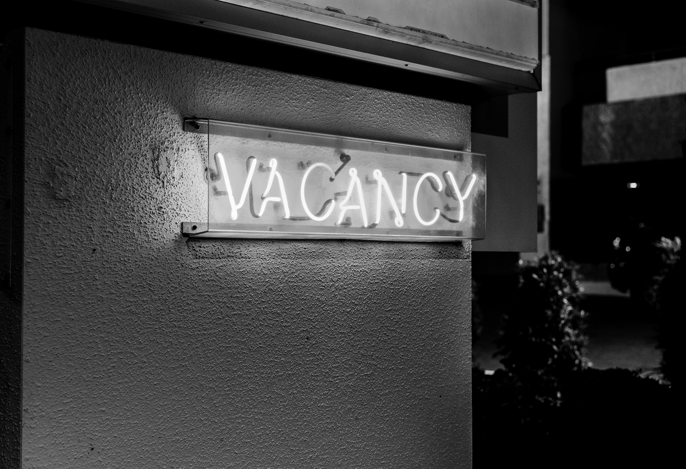 A lit-up neon Vacancy sign attached to the side of a building