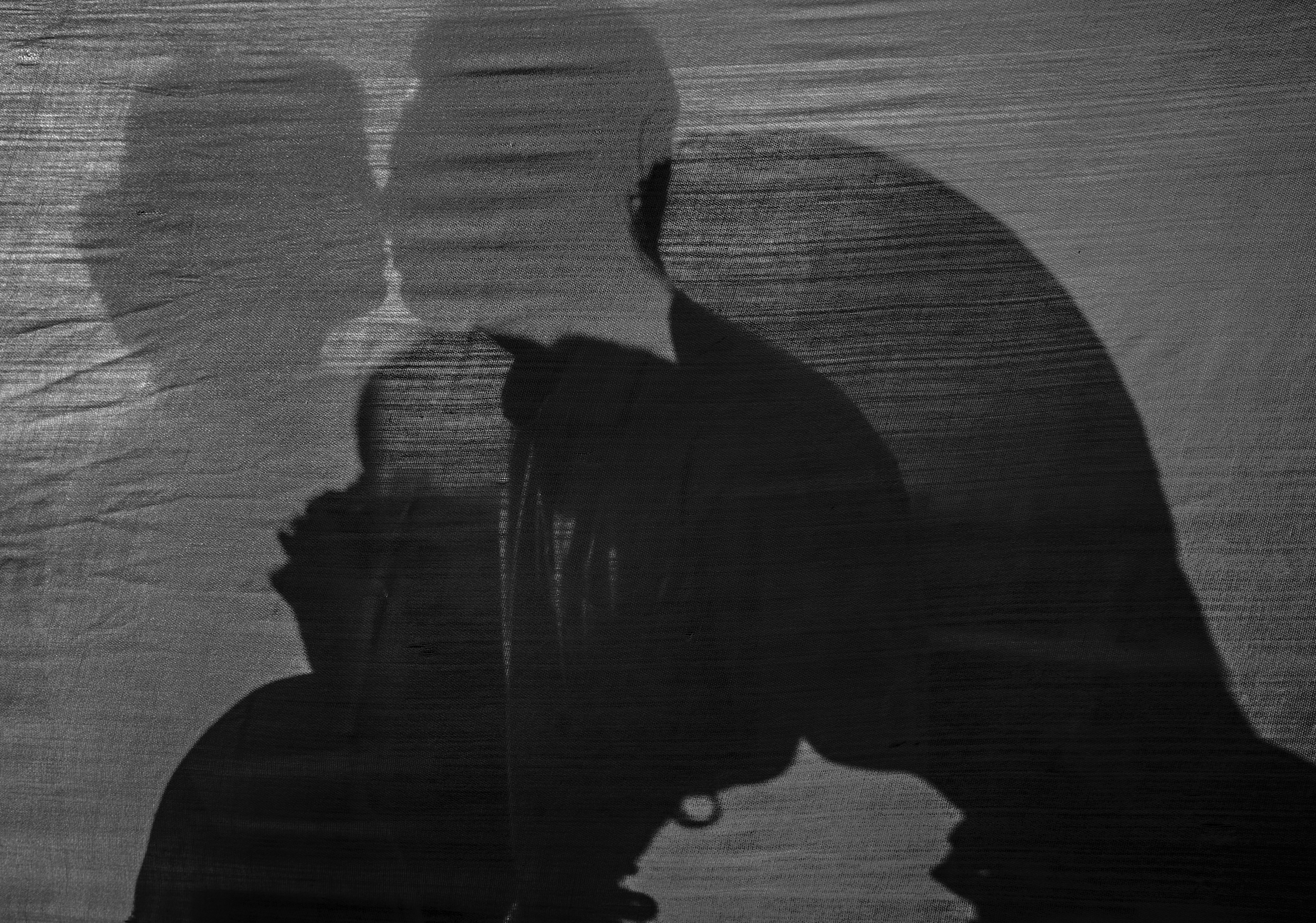 A double-exposure shot of the silhouettes of a couple that is getting closer to each other and then kissing.