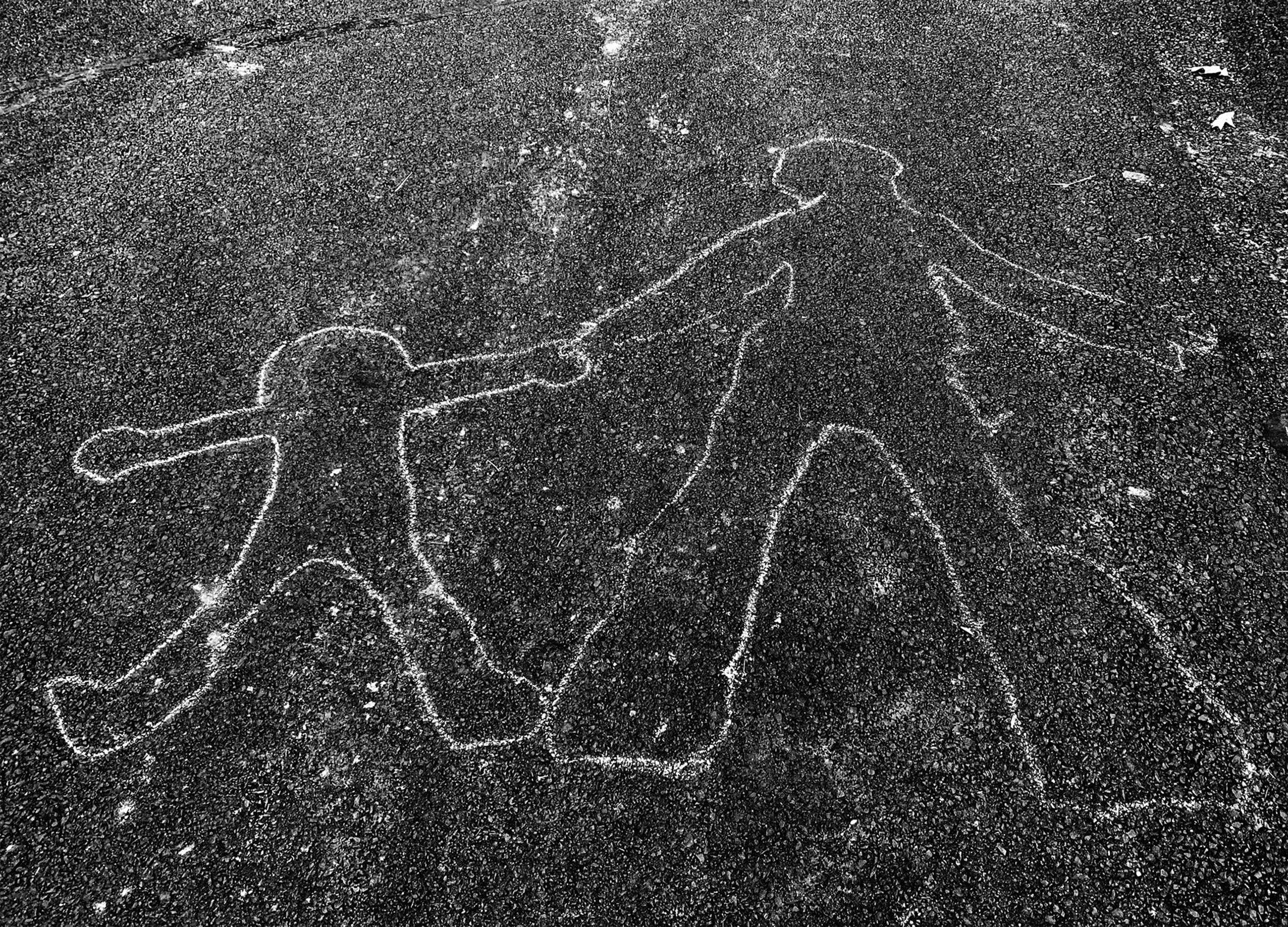 A blacktop road with a chalk outline of an adult and child walking while holding hands.