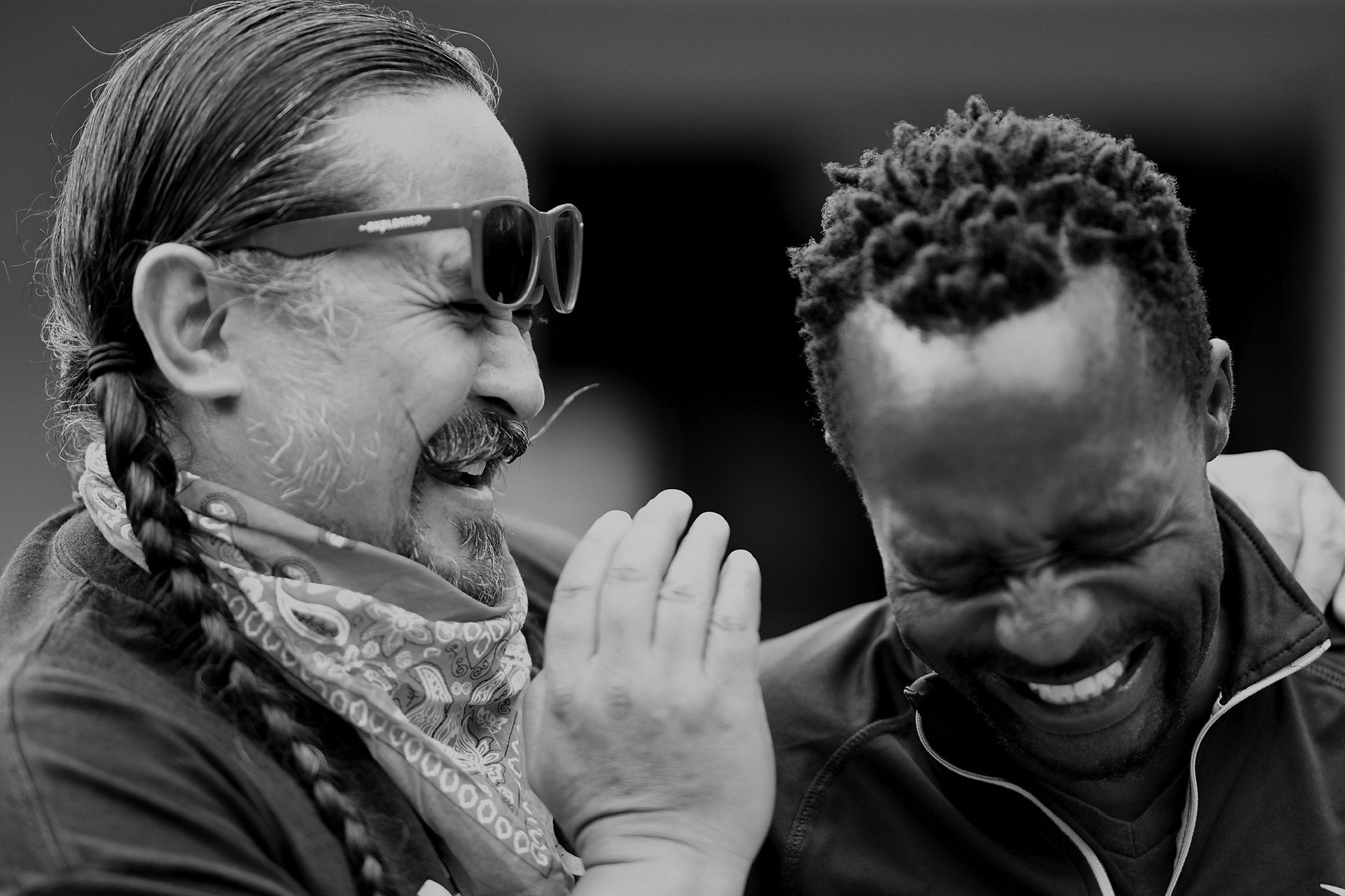 Two men, a white man and a Black man, are close together sharing a laugh.