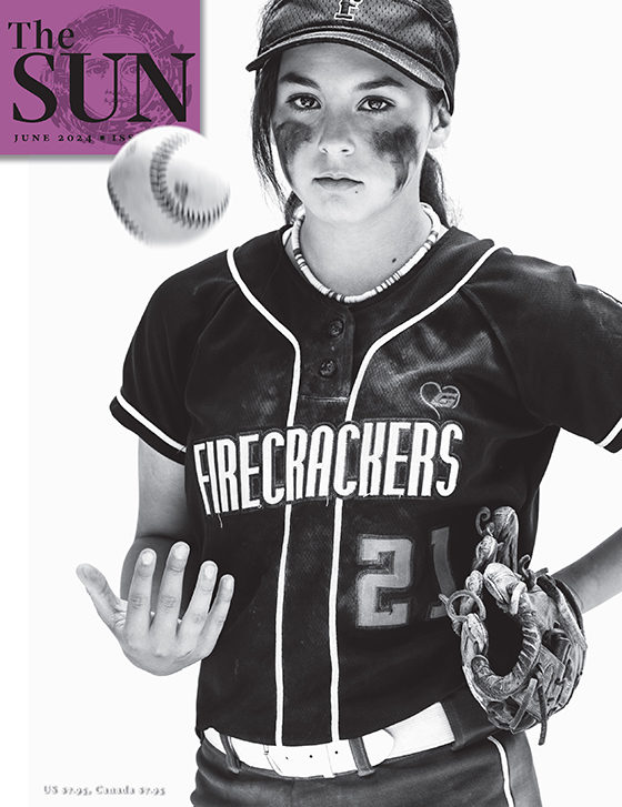 June 2024 cover of The Sun. Ella has eye black on both cheeks and a glove on her left hand as she tosses a softball up with her right. She is a pitcher and outfielder for the Firecrackers and is still in uniform after a game in La Verne, California.