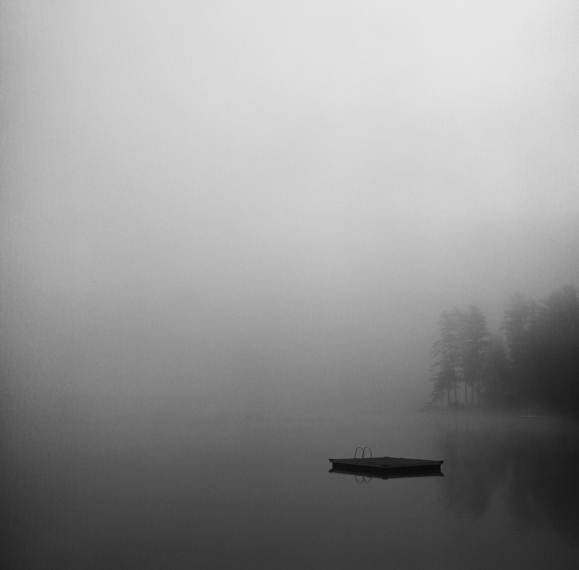 Shadowy blurred image of a lake with a small, square platform in the middle.