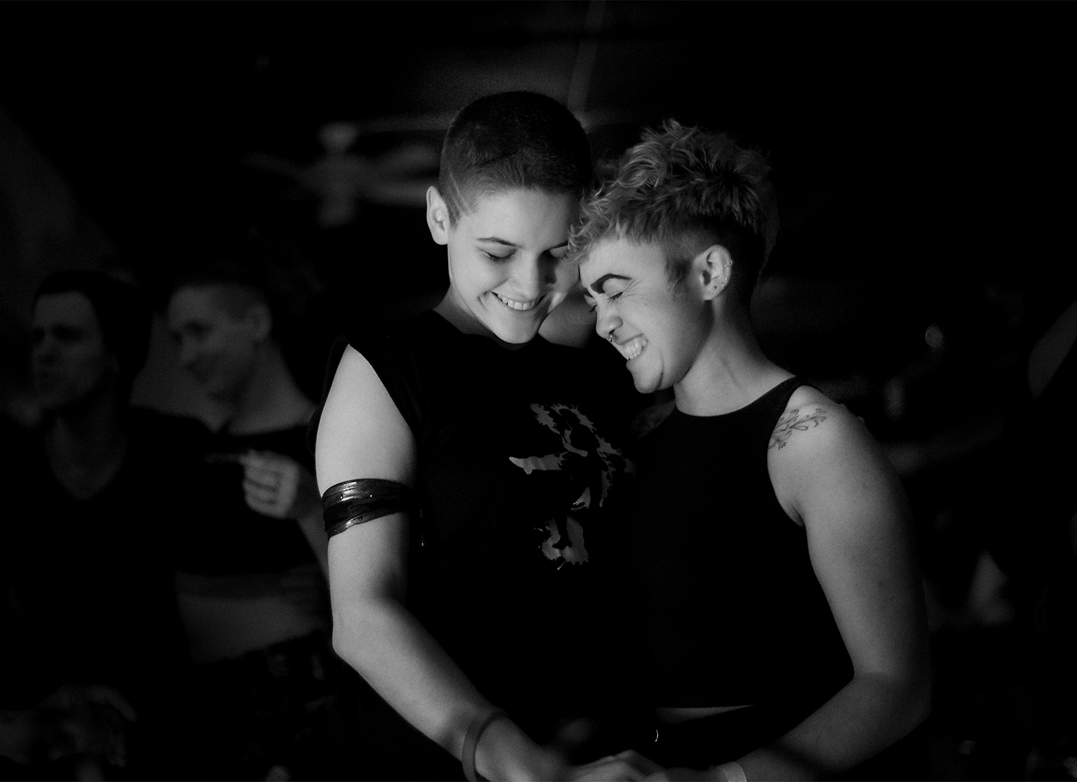 Two people are partner dancing and both are smiling with their eyes closed. They seem to be genuinely enjoying this shared moment.