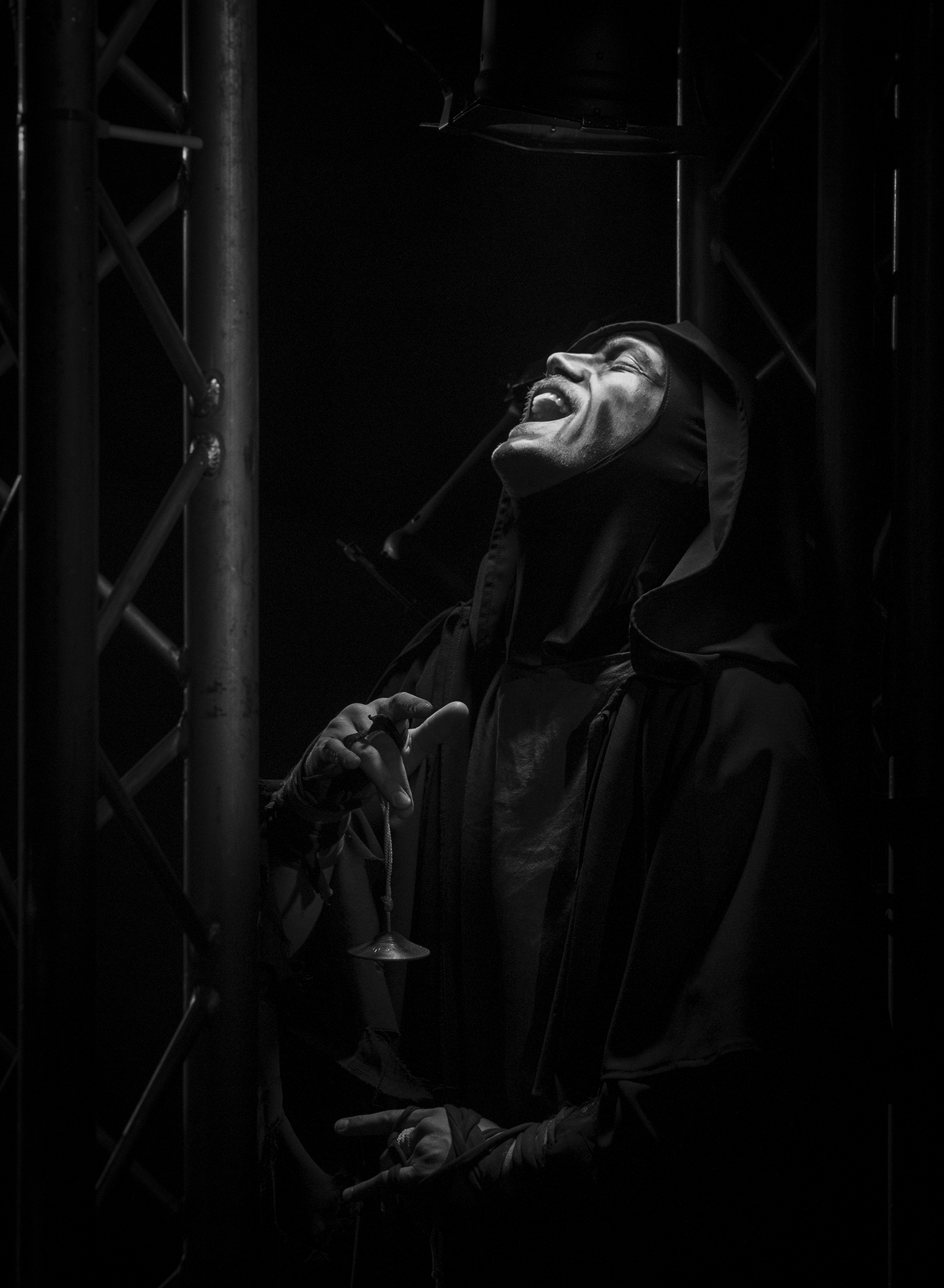 An actor in loose black clothing and a hood performs.