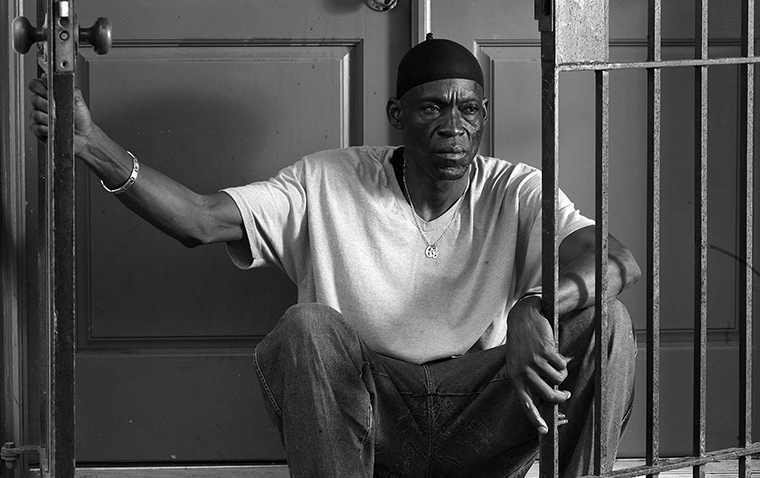 Gregory Bright sits on the floor behind the iron bar doors looking off to the side at the Innocence Project in New Orleans in February 2011.