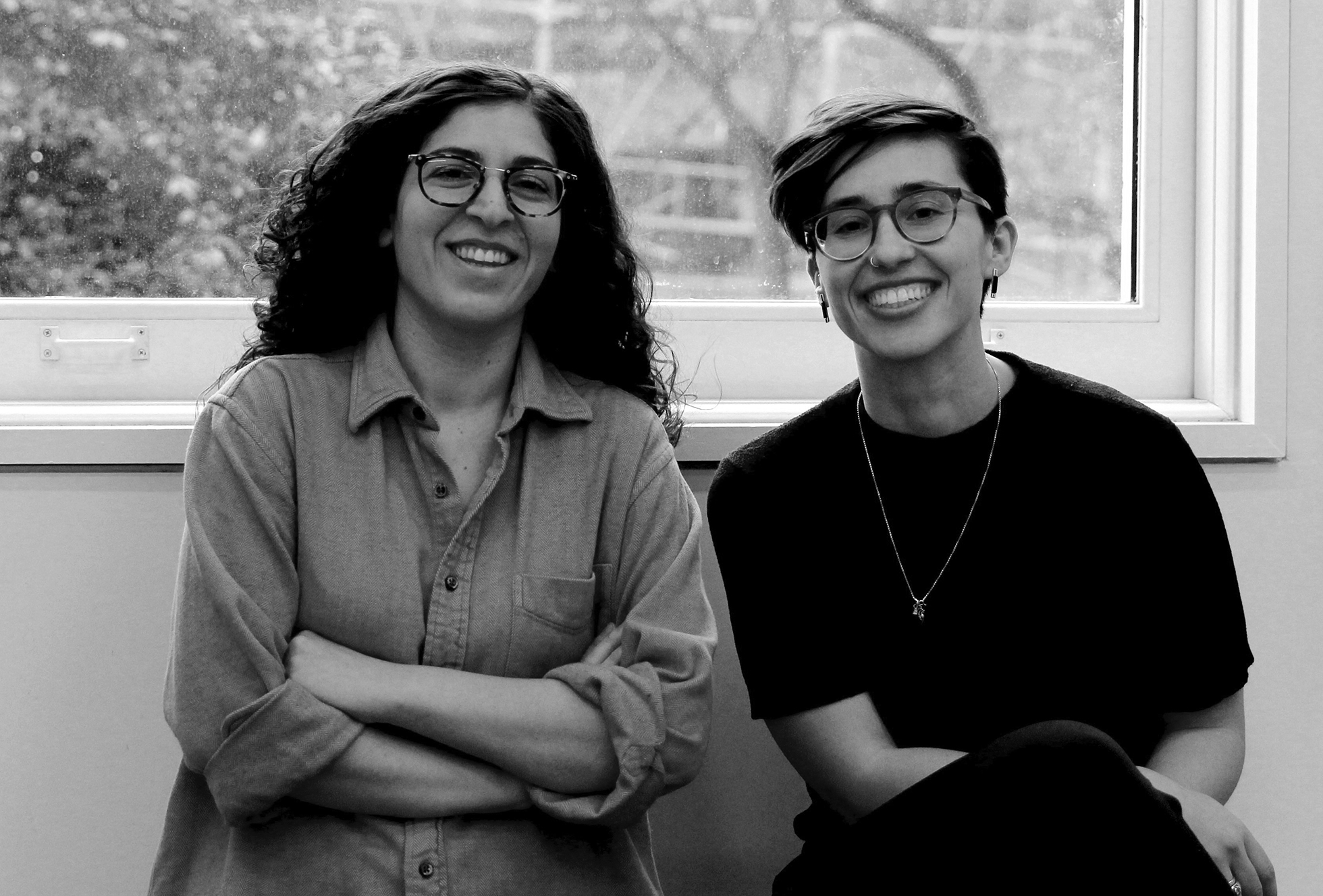 Nushin Rashidian sits with her arms crossed and smiles next to Alyson Martin, who is sitting with her legs crossed and also smiling.