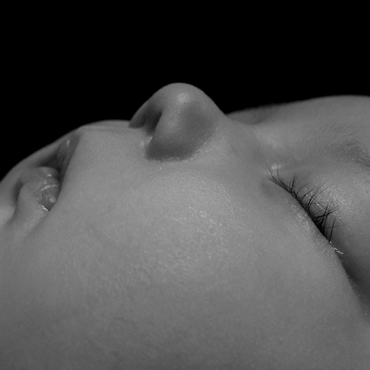 Close-up of an infant’s face who is sleeping on their back.