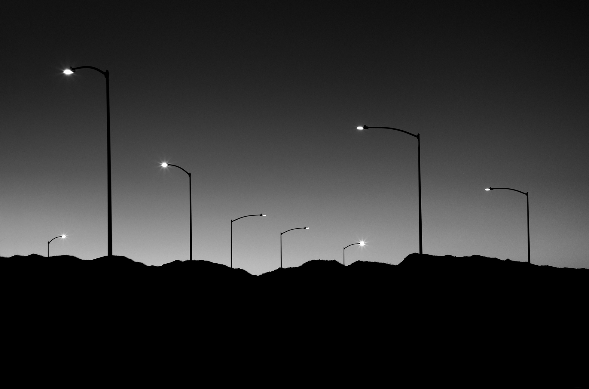 Light poles illuminated at night seen from a distance.