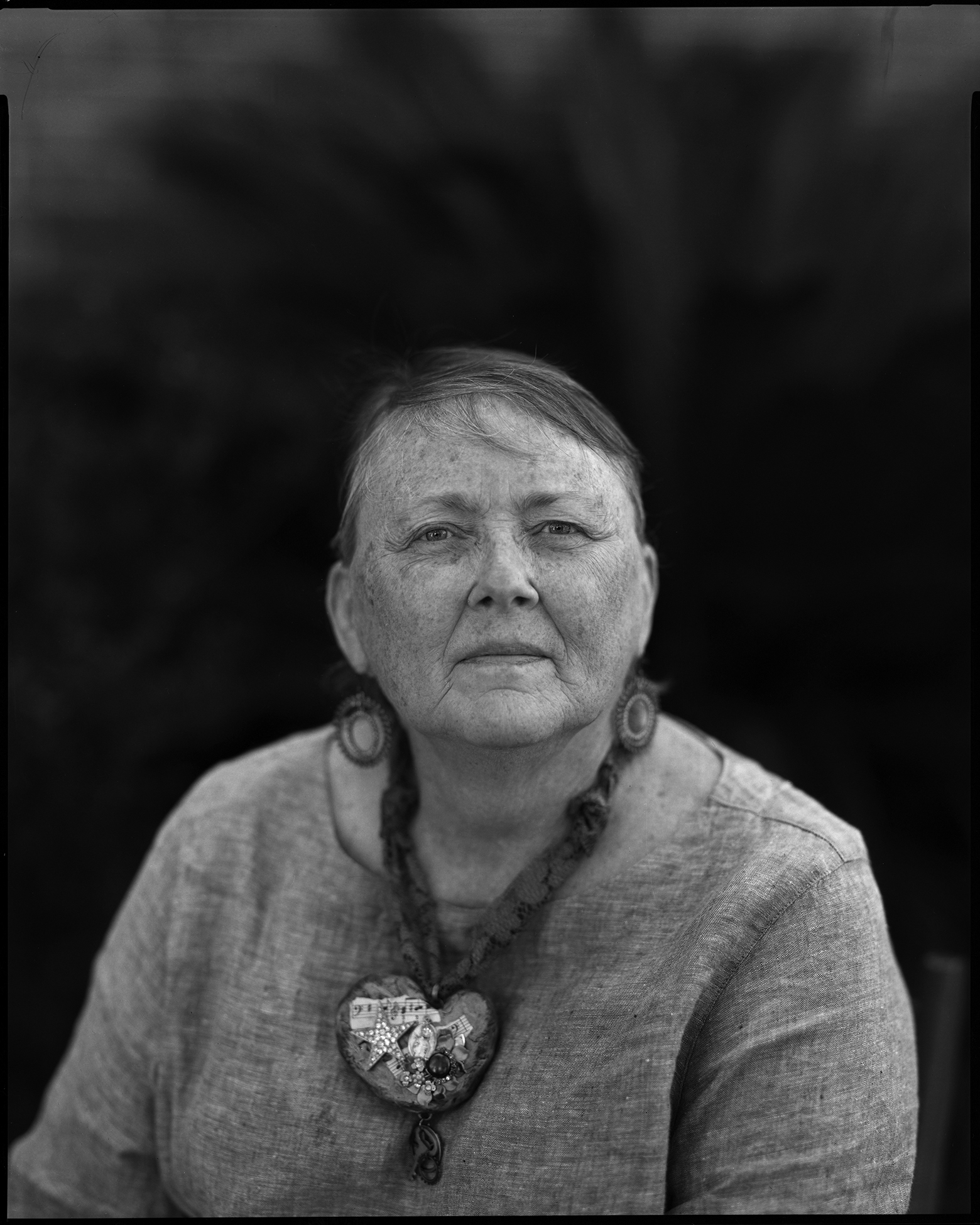 Maurice wears a linen-type shirt and a large necklace and hoop earrings while looking into the camera in Savannah, Georgia.