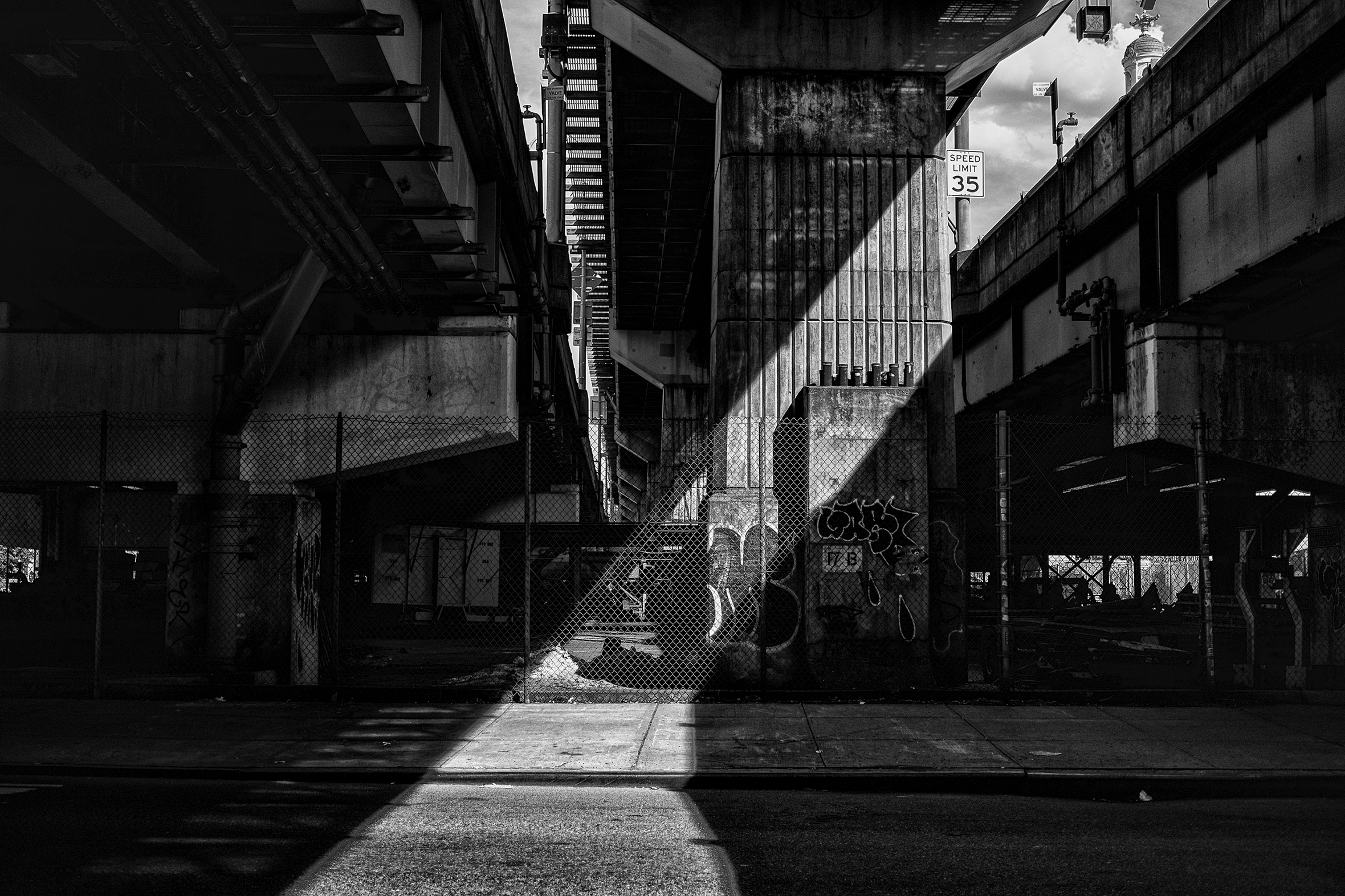 Diagonal shaft of light beneath the Williamsburg Bridge, Bedford Avenue, Brooklyn.