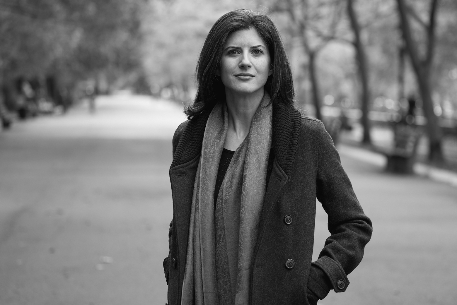 Lynn Casteel Harper stands outside in a parklike setting wearing a winter coat and scarf.