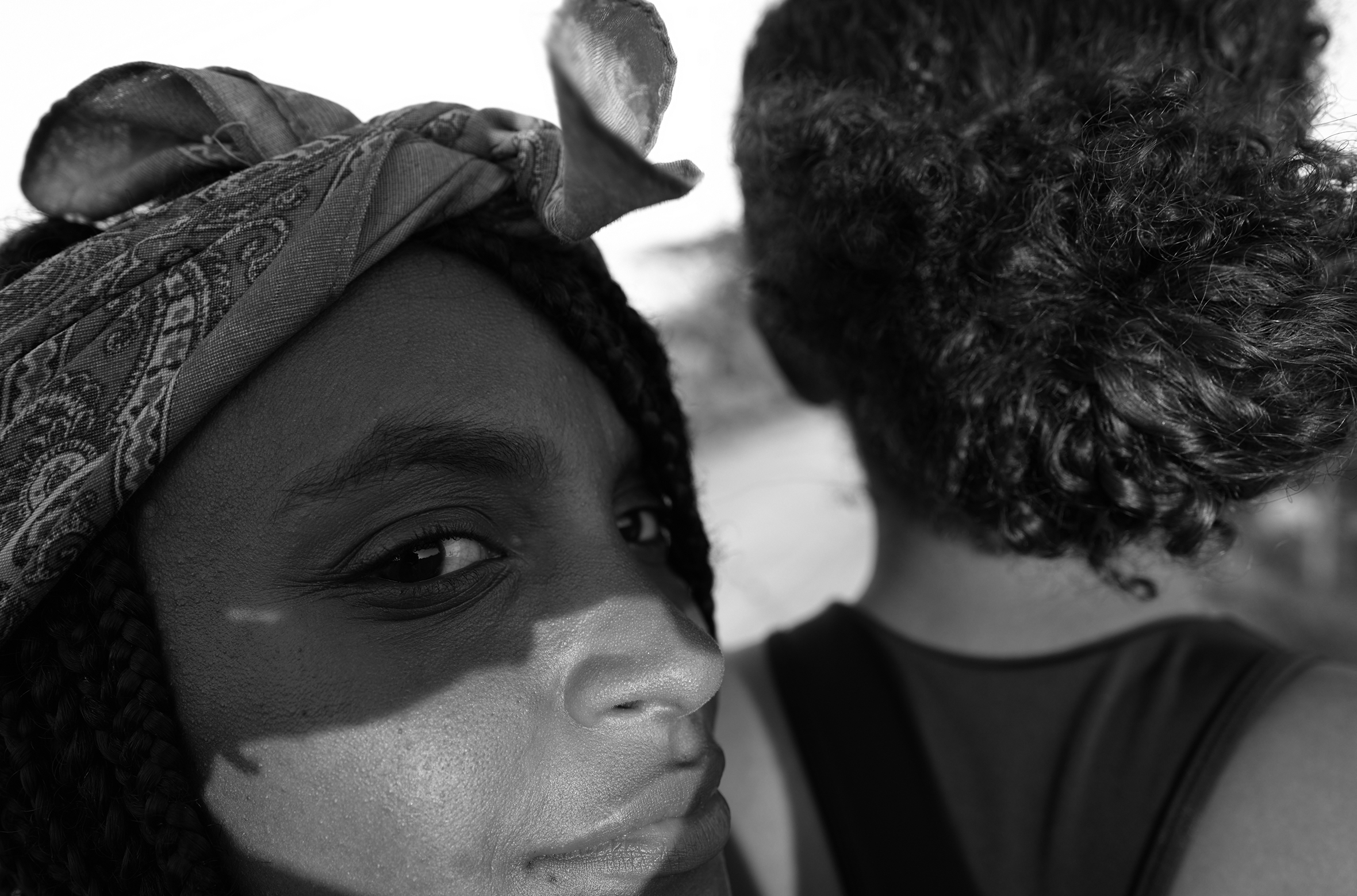 A young woman rides on the back of her friend’s dirt bike near Collantes, Oaxaca. She has a bandanna around her head and is looking back at the camera; her friend is seen from the back.