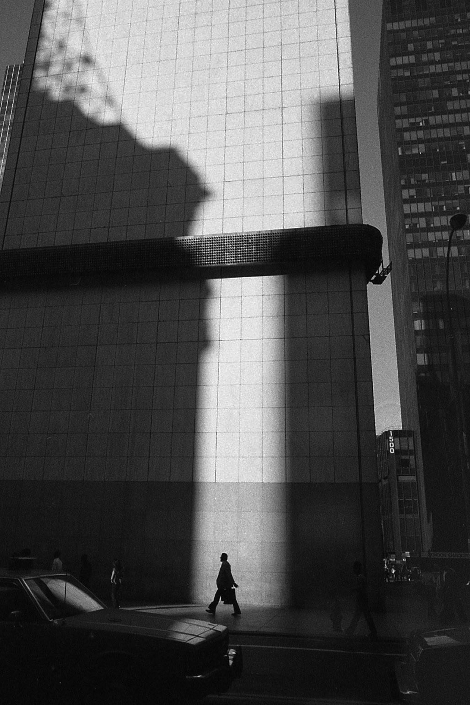 Tall office buildings in a city tower over the pedestrians on the street.